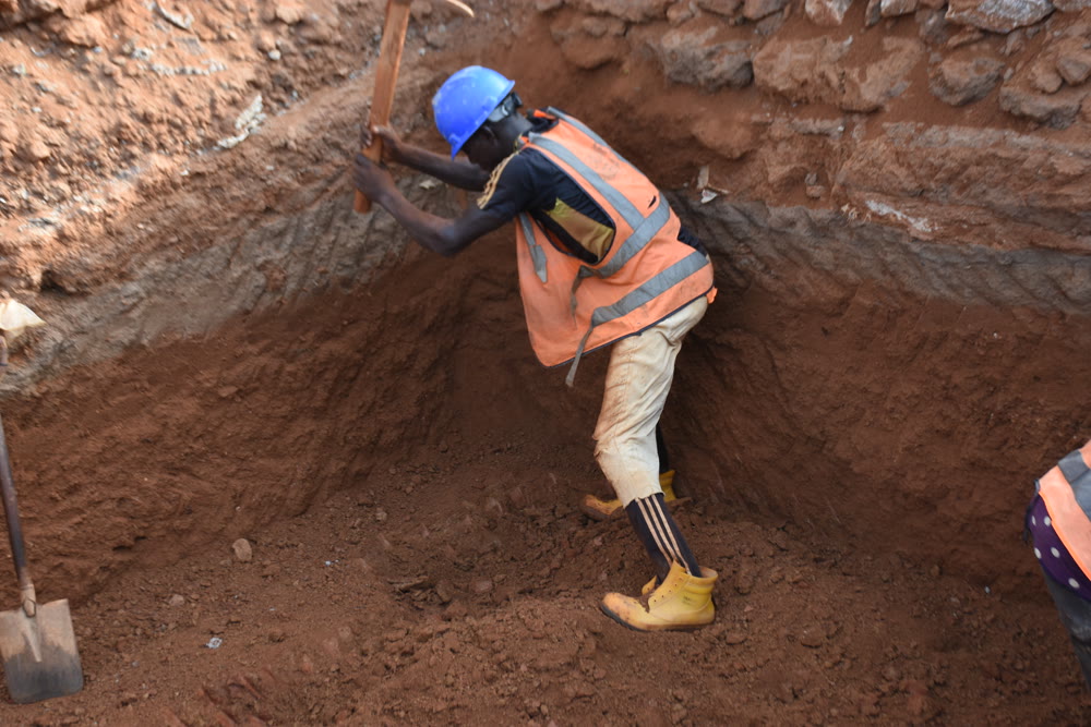 Drainage excavation in Nigeria with a worker wearing a blue hard hat and orange visibility vest